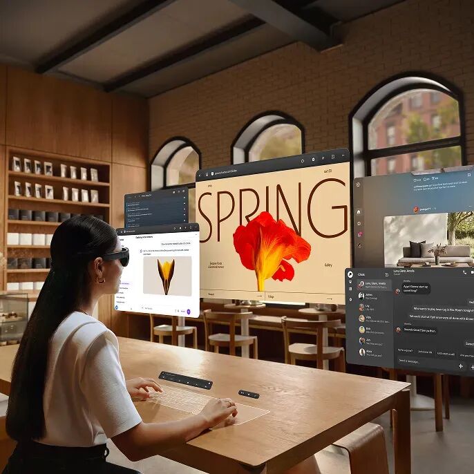 戴着 Meta VR 眼镜的人在木制咖啡桌旁使用虚拟键盘，设计、聊天和视频通话窗口漂浮在他们面前。